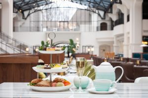 pastries on a tiered tray and teapot with teacups on saucers